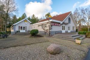 un edificio blanco con un banco delante en Luxe 4-6 pers Chalet op de Veluwe en Hoenderloo