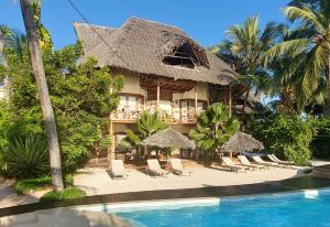 a resort with a pool and chairs and a building at Zanziblue in Matemwe