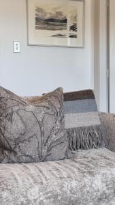 a couch with a blanket and a picture on the wall at Waterscape Apartment in Akaroa