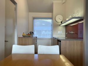 a kitchen with a table and two white chairs at Waterscape Apartment with car park in Akaroa