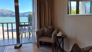 a room with a chair and a balcony with a view at Waterscape Apartment in Akaroa