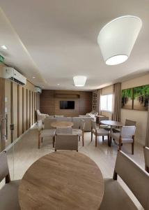 a waiting room with tables and chairs and a television at Lindo e novo apto com vista para o mar de Pituba c/garagem in Salvador +84 photos