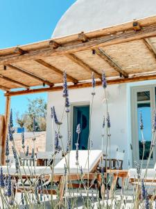 a white house with a wooden roof with purple flowers at Thimari Lodge in Fira