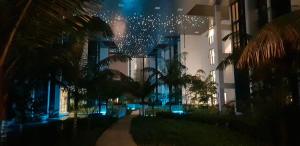 - une vue nocturne sur un bâtiment avec des palmiers et des lumières dans l'établissement M City Ampang KL city, à Kuala Lumpur