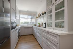 a white kitchen with white cabinets and a large window at Golden Pine Retreat in Bright