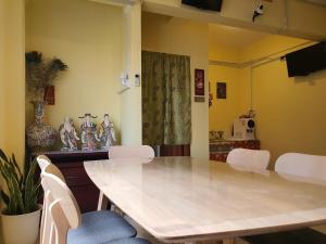 a dining room with a table and white chairs at SPOT ON 90856 Arriva Travellers in Kuching