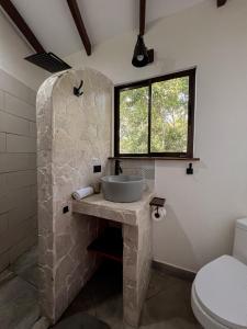 baño con lavabo de piedra y ventana en La Uvita Perdida en Uvita