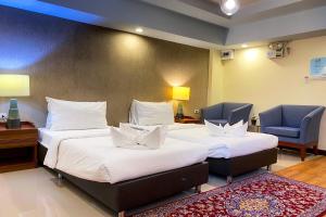 um quarto de hotel com duas camas e uma cadeira em Kim Hotel At Morleng em Bangkok