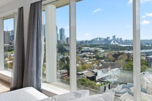 a bedroom with large windows and a view of the city at Holiday Inn Sydney Potts Point in Sydney