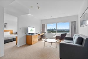 Holiday Inn Sydney Potts Point في سيدني: غرفة في الفندق بها سرير وأريكة ومكتب