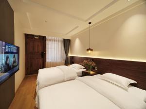 a bedroom with two white beds and a flat screen tv at Xilu Xiaoxie Inn in Lijiang
