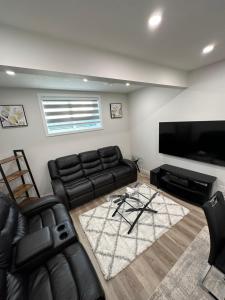a living room with a couch and a flat screen tv at 2 Bedroom 2 Washrooms Brand New Beautiful & Cozy Suite in Calgary