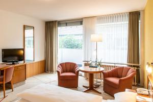 um quarto de hotel com uma cama e cadeiras e uma televisão em Hotel Frankenland em Bad Kissingen