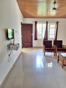 sala de estar con TV, sofá y mesa en Suvarna Grande Homes en Mangalore