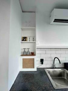 a white kitchen with a sink and a counter at The Drupadi Apartments Studio Gordy in Seminyak +15 photos