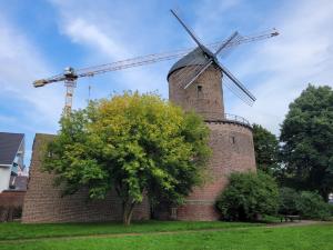 un moulin à vent en briques avec un arbre devant lui dans l'établissement Ferienwohnung Mühlenblick, à Kempen