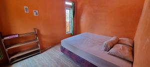 a small bedroom with an orange wall and a bed at Dam Ri Private 2nd Floor - Near Airport & Batukaras in Tjidjulang