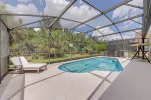 a glass house with a swimming pool and a chair at Cozy Autumn Creek Retreat in Orlando