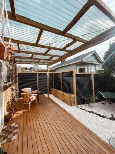 a patio with a wooden deck with a pergola at The Secret Studio, Outdoor Bath & Pizza Oven in New Plymouth