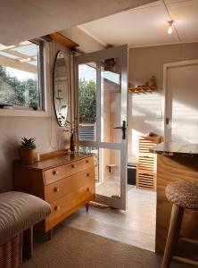 a room with a wooden dresser and a mirror at The Secret Studio, Outdoor Bath & Pizza Oven in New Plymouth