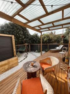 a patio with a wooden deck with a pergola at The Secret Studio, Outdoor Bath & Pizza Oven in New Plymouth