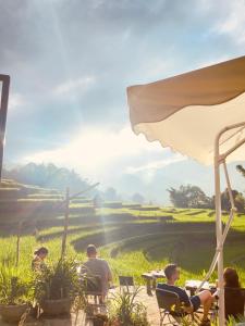 een groep mensen die aan een tafel voor een veld zitten bij Cơmlam Eco House in Sa Pa