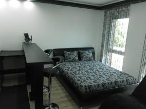a bedroom with a bed next to a desk and a window at Fészek Apartman in Debrecen
