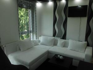 a living room with a white couch and a window at Fészek Apartman in Debrecen
