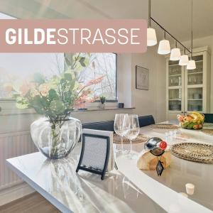 Una mesa blanca con un jarrón de flores. en Ferienwohnung "Gilde" hyggelig mit Blick ins Grüne en Glücksburg
