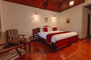 a bedroom with a bed and a chair at Cocobay Resort Kumarakom in Kumarakom