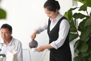 a woman holding a cup of coffee and a man at Pleiku & Em Hotel by Gia Lai Tourist in Pleiku