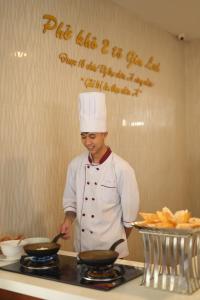 un chef de pie en una cocina preparando comida en Pleiku & Em Hotel by Gia Lai Tourist en Pleiku
