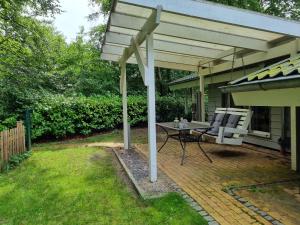 a patio with awning and a table and a chair at Ferienhaus Paulsen - gemütliches Häuschen mit vollständig eingezäuntem Garten und Kamin in Silberstedt