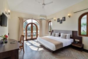 a bedroom with a large bed and a desk at Resort Rio in Arpora