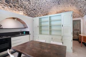 a kitchen with white cabinets and a wooden table at La credenza, borgo dei pescatori in Cervo