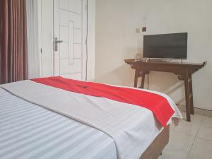 Schlafzimmer mit einem Bett und einem Schreibtisch mit einem TV in der Unterkunft RedDoorz @ Hotel Arwana Safari Puncak in Tagalbato