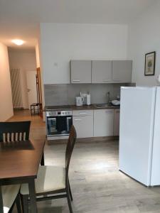eine Küche mit weißen Schränken, einem Tisch und einem Kühlschrank in der Unterkunft Gasthof Tatenhausen Ferienwohnungen in Tatenhausen