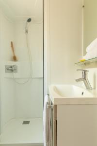 a white bathroom with a shower and a sink at Gitavillage Le Marze in Marina di Grosseto