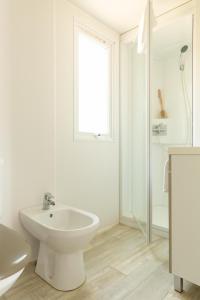 a white bathroom with a toilet and a sink at Gitavillage Le Marze in Marina di Grosseto