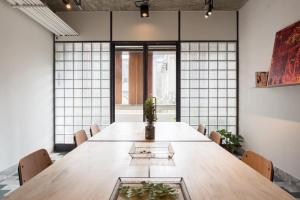 a large wooden table in a room with windows at 軟寓 nńg inn in Tainan