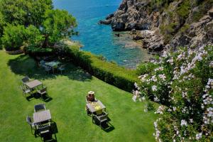 a person sitting at a table in the grass near the water at Hotel Capo D'Uomo in Talamone