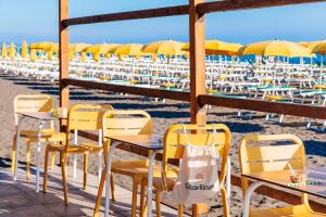 a table and chairs on a beach with umbrellas at Gitavillage California in Montalto di Castro
