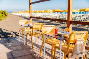 a row of tables and chairs on a beach with umbrellas at Gitavillage California in Montalto di Castro