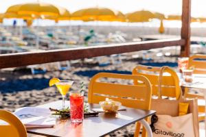 a table with two drinks on top of a beach at Gitavillage California in Montalto di Castro