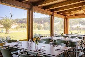 a dining room with tables and chairs and large windows at Gitavillage California in Montalto di Castro