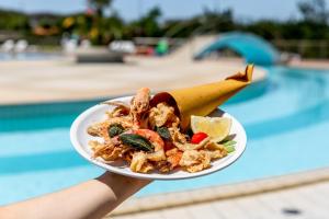 a person holding a plate of food next to a pool at Gitavillage California in Montalto di Castro