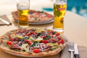 two pizzas sitting on a table with two glasses of beer at Gitavillage California in Montalto di Castro