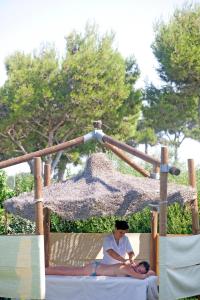 a woman and a child laying on a bed under an umbrella at Gitavillage California in Montalto di Castro