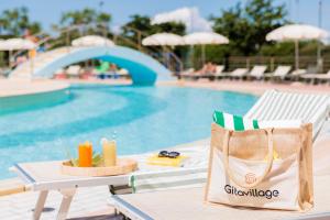 a pool with a table with a drink and a beach chair at Gitavillage California in Montalto di Castro