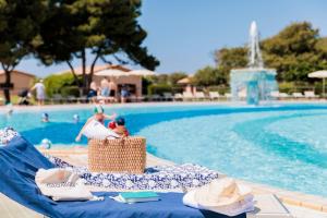 a swimming pool with a blue lounge chair with hats on it at Gitavillage California in Montalto di Castro